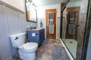 Bathroom featuring a shower with door, toilet, tile patterned flooring, vanity, and a textured ceiling