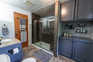 Bathroom with tile patterned floors, an enclosed shower, vanity, and toilet