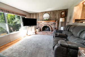 Living room with wood walls, hardwood / wood-style floors, plenty of natural light, and a fireplace