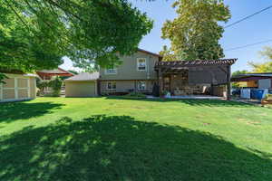 Back of property with a lawn, a pergola, and a patio area