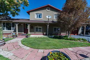 View of front of property with a garage, a front yard, and covered porch