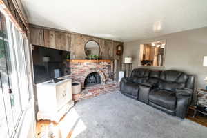 Living room with wooden walls, plenty of natural light, a brick fireplace, and wood-type flooring