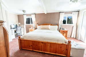 Bedroom with ceiling fan, beam ceiling, carpet, and multiple windows