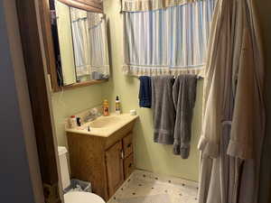 Bathroom with patterned flooring, vanity, and toilet