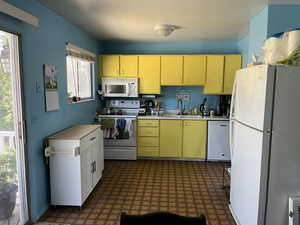 Kitchen with sink, white appliances, and dark  patterned flooring