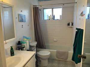 Full bathroom featuring patterned flooring, vanity, shower / tub combo, and toilet