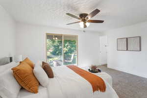 Carpeted bedroom featuring ceiling fan, a textured ceiling, and access to exterior