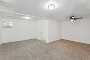 Carpeted spare room with ceiling fan and a textured ceiling