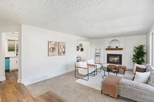 Living room featuring brick wall, light hardwood / wood-style floors, sink, a fireplace, and a textured ceiling