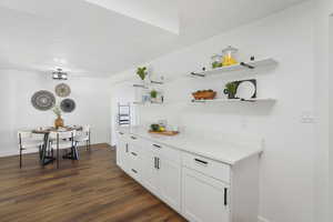 Bar featuring dark hardwood / wood-style flooring and white cabinetry