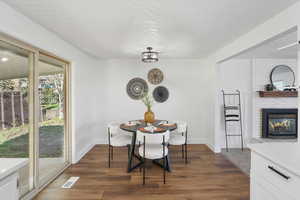 Dining room featuring dark hardwood / wood-style flooring, a brick fireplace, and brick wall