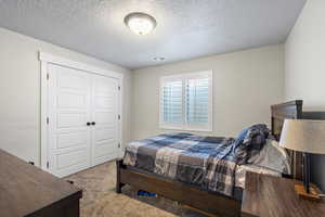 Bedroom featuring light colored carpet, a closet, and a textured ceiling