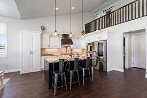 Kitchen featuring premium range hood, stainless steel appliances, and an island with farmhouse sink