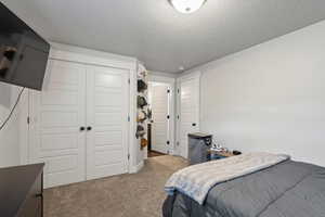 Carpeted bedroom featuring a textured ceiling and a closet