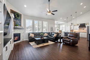 Living room featuring a fireplace built in shelving, high vaulted ceiling, and ceiling fan