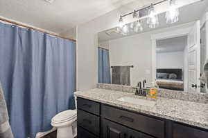 Bathroom featuring a textured ceiling, vanity, and toilet