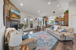 Living room with dark hardwood / wood-style flooring, a fireplace, high vaulted ceiling, and french doors