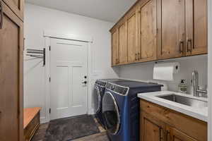 Laundry area featuring sink, washing machine and clothes dryer, cabinets, and dark hardwood / wood-style floors