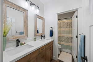 Bathroom with toilet and dual bowl vanity