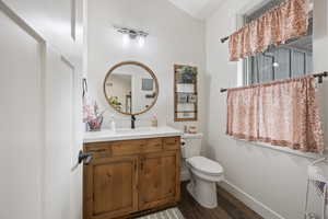 Bathroom featuring wood-type flooring, toilet, and vanity