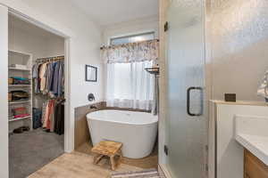 Primary Bathroom featuring wood-type flooring, a tub to relax in, and tile walls