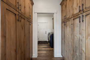 Laundry and storage cabinets with dark hardwood / wood-style flooring and washer and dryer