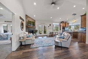 Living room featuring a stone fireplace, french doors, dark carpet, ceiling fan, and lofted ceiling