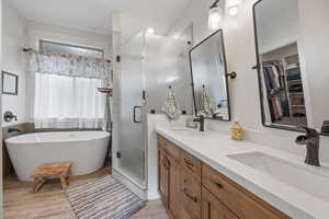 Primary Bathroom with separate shower and tub, double sink vanity, and wood-type flooring