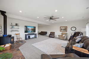 Tiled living room featuring ceiling fan and a wood stove