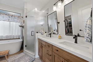 Primary Bathroom featuring shower with separate bathtub and double sink vanity