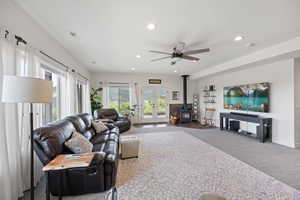 Living room with ceiling fan, french doors, carpet floors, and a wood stove