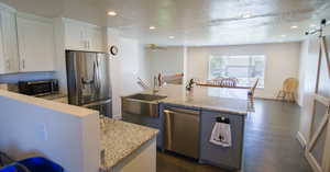 Kitchen featuring dark wood-type flooring, light stone countertops, sink, a center island, and stainless steel appliances