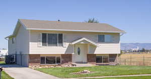 Bi-level home featuring a mountain view, central air condition unit, and a front yard