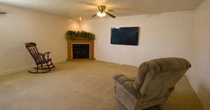 Living room featuring ceiling fan, light colored carpet, and a textured ceiling