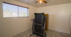 Workout area with ceiling fan, light tile patterned flooring, and a textured ceiling