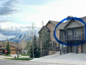 Exterior space with a garage, a mountain view, driveway, and stone siding