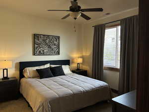 Bedroom featuring carpet floors, a ceiling fan, visible vents, and multiple windows