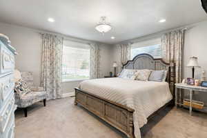 Primary bedroom featuring light carpet and a textured ceiling