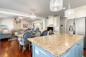 Kitchen featuring dark hardwood / wood-style floors, a kitchen island, light stone counters, decorative light fixtures, and lofted ceiling