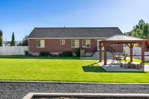 Back of property featuring a lawn, a gazebo, and a patio