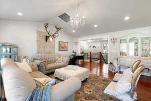 Living room with vaulted ceiling, a chandelier, and dark hardwood / wood-style floors