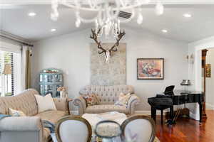 Living room with an inviting chandelier, lofted ceiling, and hardwood / wood-style floors