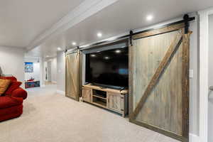 Living room with a barn door and light carpet