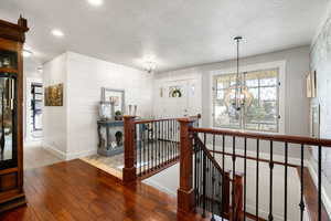 Hallway featuring a textured ceiling, light hardwood / wood-style floors, and a chandelier