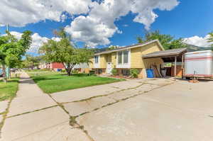 View of front facade featuring a carport and a front yard.