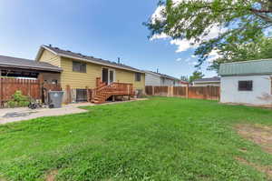 Exterior space featuring a patio area, a yard, and a deck.