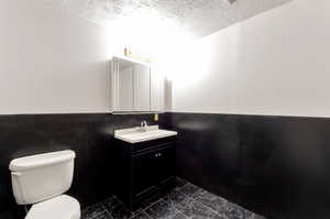 Bathroom with tile patterned floors, a textured ceiling, vanity, and toilet.