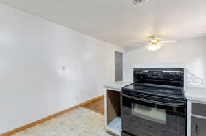 Kitchen with black range with electric stovetop, light wood-type flooring, and ceiling fan