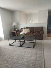 Living room with a notable chandelier, a textured ceiling, and carpet floors