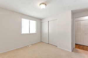 Unfurnished bedroom featuring a closet and light colored carpet.